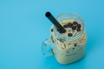 glass of Iced milk green tea with bubble boba on the blue background 