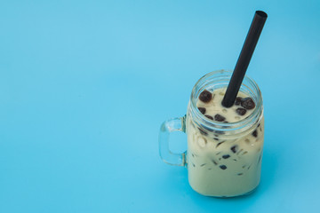 glass of Iced milk green tea with bubble boba on the blue background 