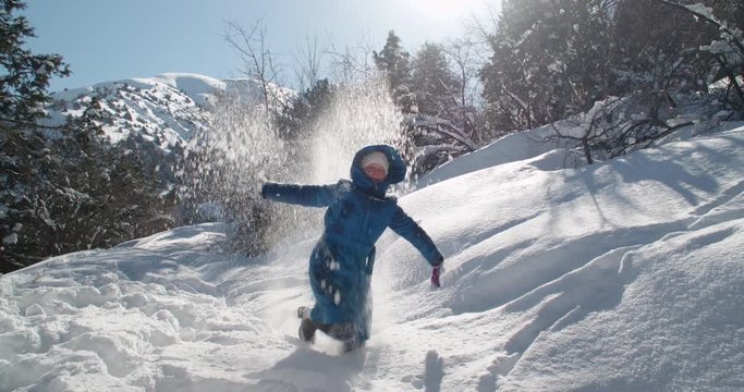 Winter girl rejoices and plays with snow in the mountains, slow motion video 4k