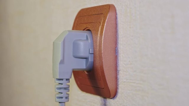 Gray electrical plug is inserted into the socket