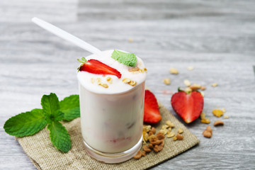 yogurt and strawberry in glass with mint on table background