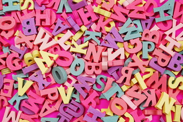 Fototapeta na wymiar random colorful letterpress alphabet top view on pink background