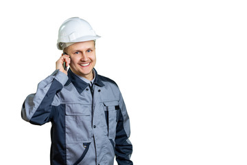 Handsome young builder engineer in overall talking on mobile phone isolated on a white background.
