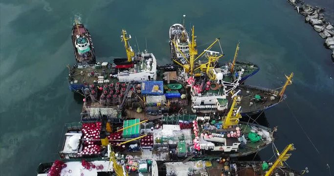 Top spinning aerial view of a few fishing boats moored near quay. Nevelsk, Sakhalin island, Russia. Tatar Strait, sea of Japan