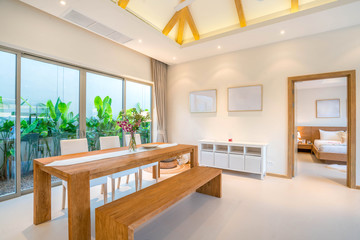 Luxury interior design in living room of pool villas. Airy and bright space with high raised ceiling and wooden dining table
