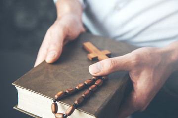 man hand holding  cross with Bible