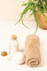 Obraz na płótnie Canvas Set for spa treatments soft clean towels salt soap on the background tropical plant. Vertical frame. Selective focus.
