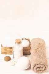 Obraz na płótnie Canvas Set for spa treatments. Soft clean towels bath salt a piece of natural soap laid on a light wooden background.