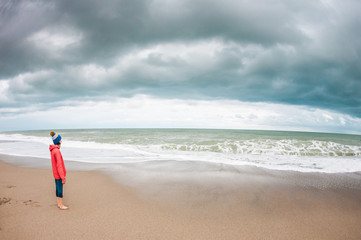 Fototapeta na wymiar Barefoot woman looks at the winter sea.