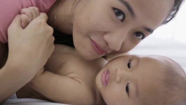 young asian mother playing with her newborn baby