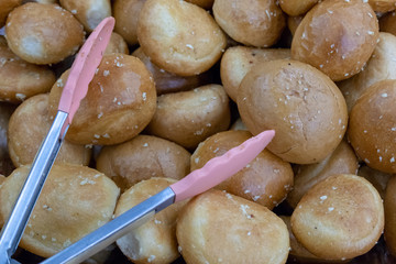 Bread tongs are lying on buns. Food background.