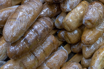 Baked goods wrapped in a transparent film. Food background of bread loaves. The concept of shopping at the grocery supermarket.