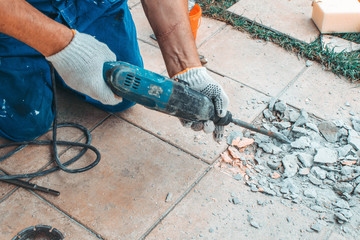 Professional builder man in dusty uniform, tile and perforator. Concept overhaul, renovation,...