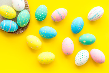 Easter traditions. Colorful Easter eggs in basket on yellow background top view