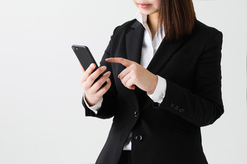 白背景スーツの女性がスマートフォンの操作をしている姿