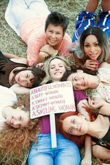 Group of women in nature with a poster ""A beautiful woman is a smiling woman"  International Womens Day concept.	