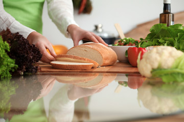 Unknown human hands cooking in kitchen. Woman slicing bread. Healthy meal, and vegetarian food concept