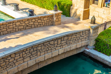 Decorative stone bridge through an artificial channel with azure water.
