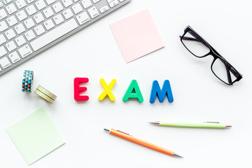 Preparing to exam. Word exam lined with colorful letters near computer keyboard and supplies on white background top view