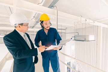 Asian engineers look at blueprint..