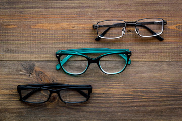 Set of glasses with transparent lenses on dark wooden background top view space for text