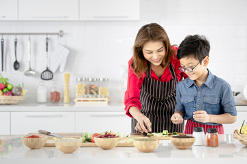 Mom is teaching children to cook food from vegetables in the kitchen.