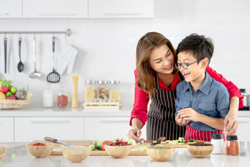 Mom is teaching children to cook food from vegetables in the kitchen.