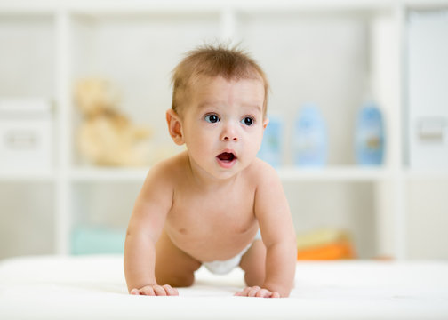 Funny baby boy weared diaper crawls in nursery