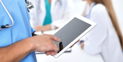 Surgeon doctor using tablet computer, close-up of hands at touch pad screen