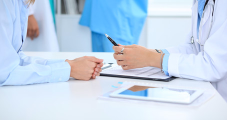 Doctor and patient discussing something, just hands at the table, white background