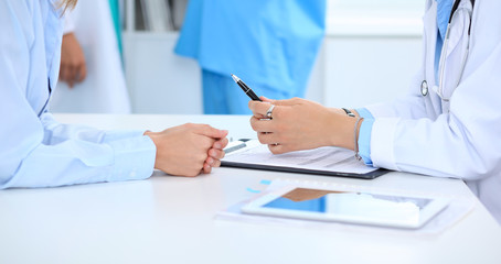 Fototapeta premium Doctor and patient discussing something, just hands at the table, white background
