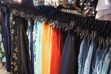 Metal rack with hangers of colorful fashionable trousers in contemporary shop, close up