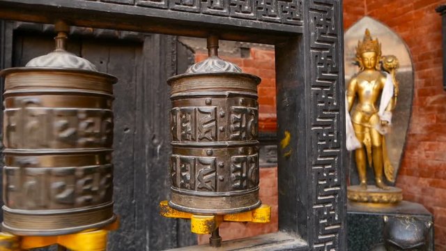 Row of aged religious prayer wheels or drums with mantra Om Mani Padme Hum in yard of temple, Durbar Square, Nepal, Kathmandu. Tibetian buddhism