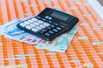 Qatar Riyal Bank Notes on spreadsheet report background With Calculator