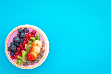 Superfoods. Acai smoothie bowl with fresh fruits, berries, chia seeds on blue background top view copy space