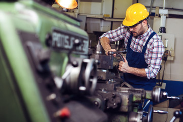 Turner worker is working on a lathe machine in a factory