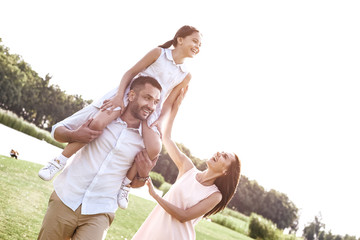 Bonding, Family of three walking on grassy field girl sitting on