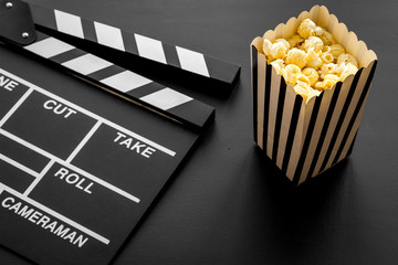 Movie premiere concept. Clapperboard and popcorn on black background