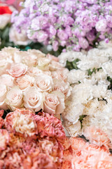 Floral carpet, flower texture, shop concept. Beautiful fresh blossoming flowers roses, spray roses, lilac gillyflower and carnation. Blossom of pastel color in vases and pails. Top view.