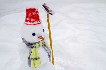 Snowman in red hat and scarf made by children. Closeup, selective focus