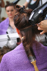 Girl in beauty salon while an hair stylist dry her hair