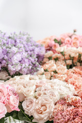 Floral carpet, flower texture, shop concept. Beautiful fresh blossoming flowers roses, spray roses, lilac gillyflower and carnation. Blossom of pastel color in vases and pails. Top view.