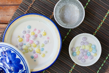 Color of Rice Dumpling in Coconut Milk (Bua Loy) in white bowl on wooden table for served in party. Famous dessert in Thailand. Sweet and delicious food.