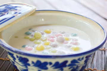 Color of Rice Dumpling in Coconut Milk (Bua Loy) in white bowl on wooden table for served in party. Famous dessert in Thailand. Sweet and delicious food.
