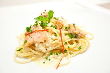 Spaghetti with salmon, cream cheese and spinach close-up on white plate