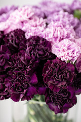 beautiful carnations flowers in a vase on a table . Bouquet of dark violet, purple and pink multicolor flower. Decoration of home. Floral texture, Wallpaper.