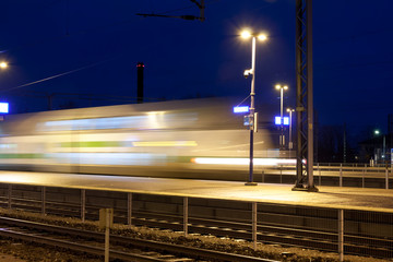 Train in motion on the station at night, long exposure photo.