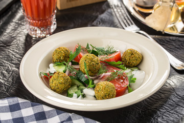 Vegetarian green salad with falafel and glass of tomato juice on the table