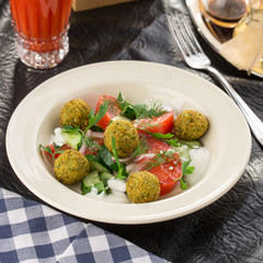 Vegetarian green salad with falafel and glass of tomato juice on the table