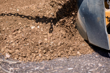 Road construction workers repairing highway road on sunny summer day. Loaders and trucks on newly made asphalt. Heavy machinery working on street. Road curbs being constructed with gravel  